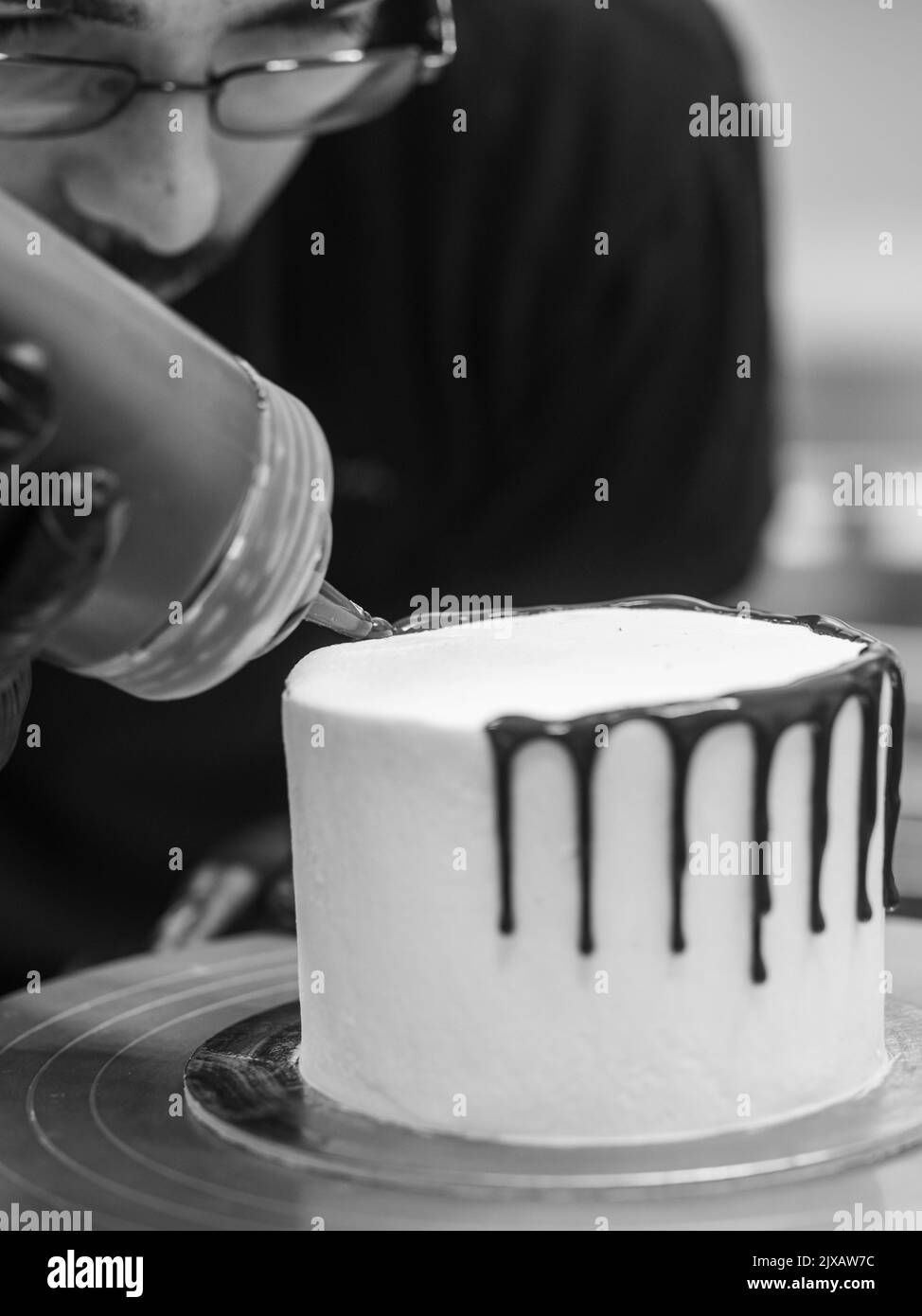 Ein nicht erkennbarer Arbeiter, der einen süßen, tropfenden Schoko-Kuchen und Beeren zubereitet Stockfoto