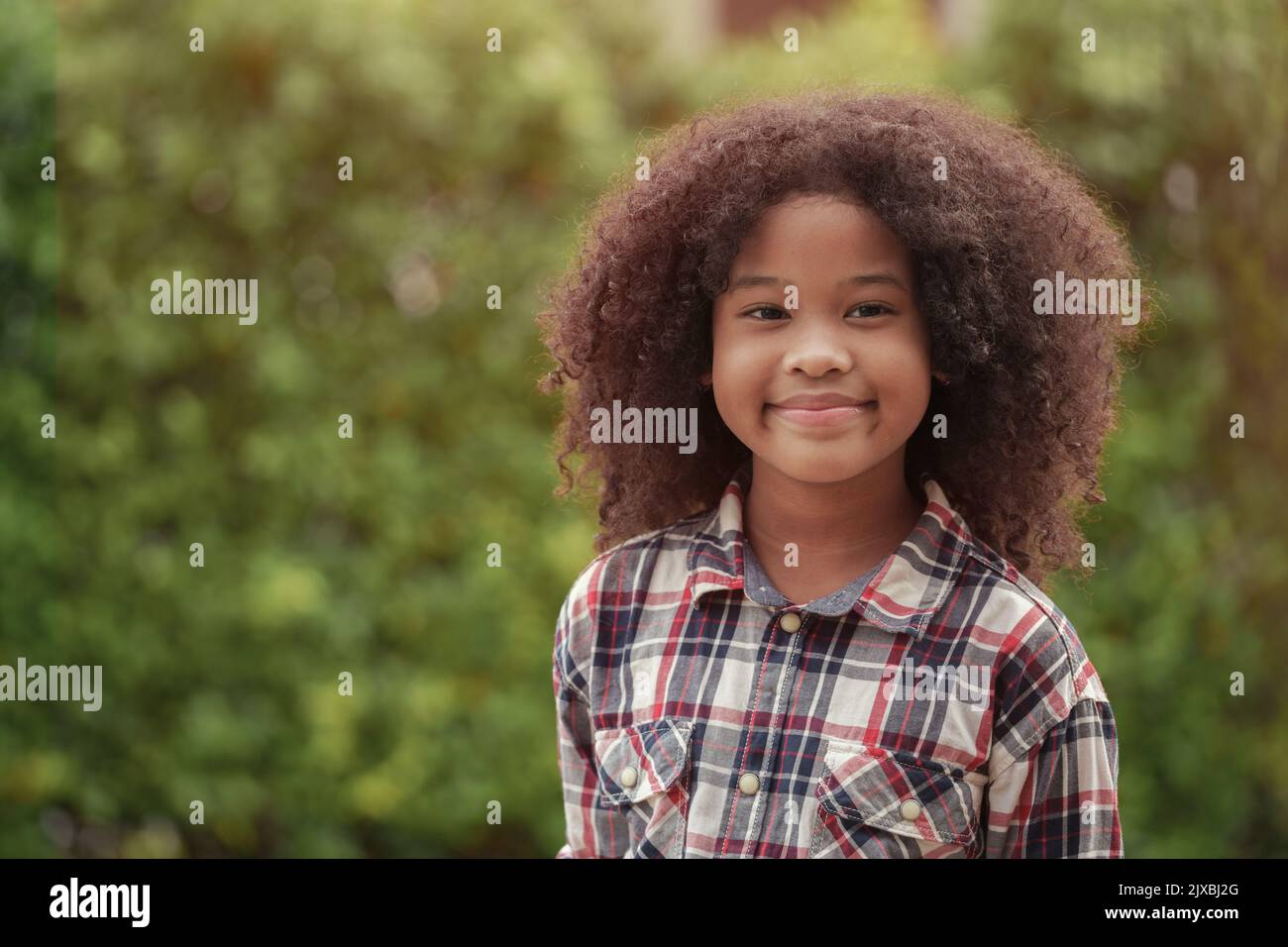 Afroamerikanisches Mädchen lächelt im Garten oder im Freien. Stockfoto