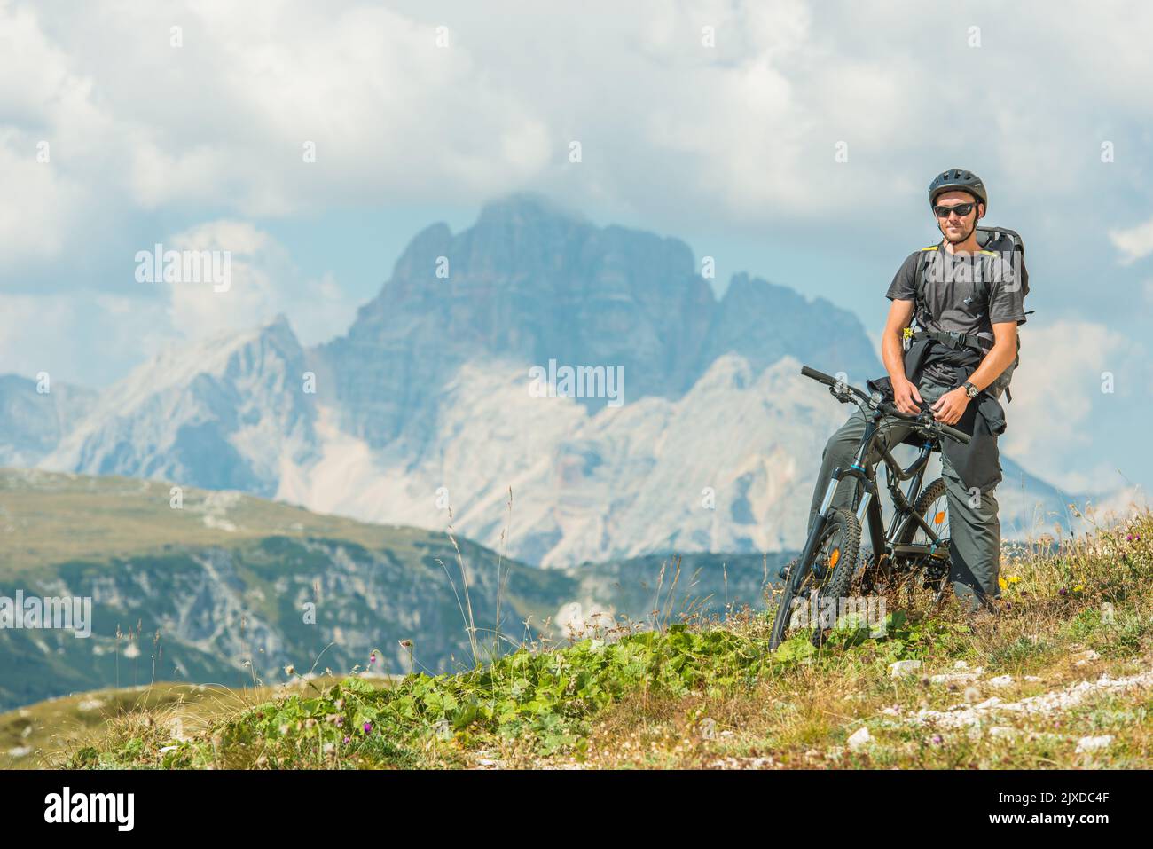Glücklicher Kaukasischer Tourist mittleren Alters mit einem Rucksack, der Berge auf seinem Fahrrad erkundet. Zwischenstopp Während Des Long Biking Trail. Aktives Lifestyle-Thema. Stockfoto