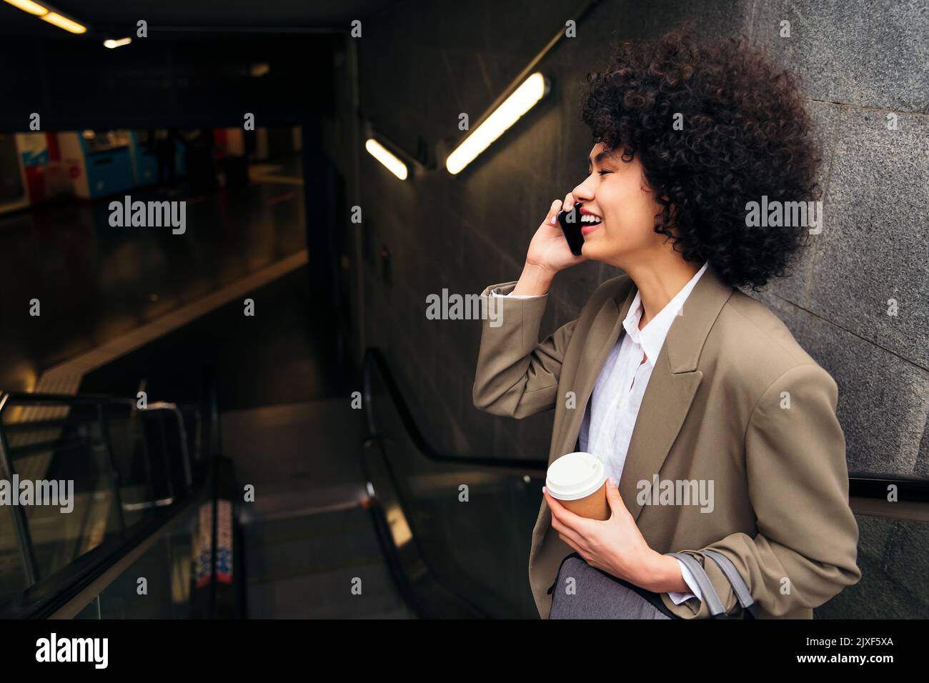 Eine Geschäftsfrau, die mit der Rolltreppe telefoniert Stockfoto