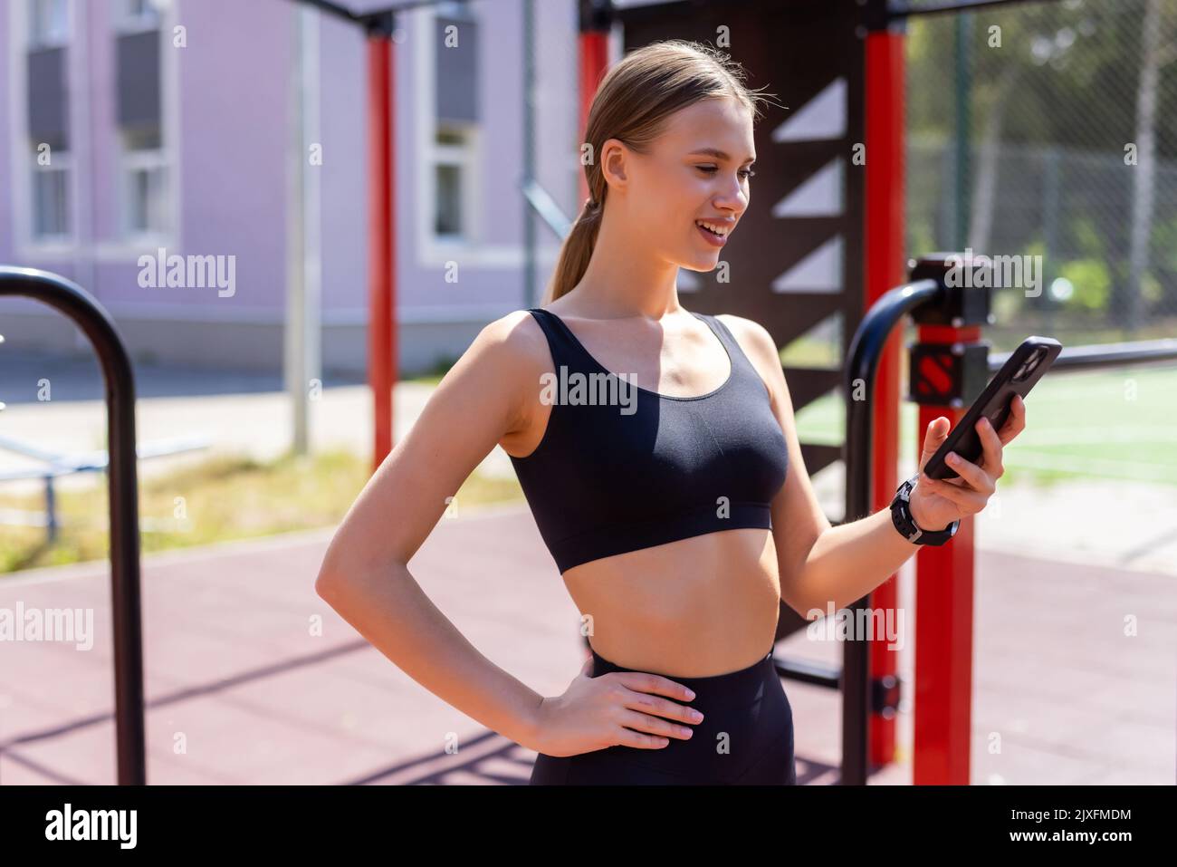 Eine athletische Frau, bevor sie mit dem Laufen beginnt, ihre Smartphone-App und ihr Fitnesszubehör aufstellt Stockfoto