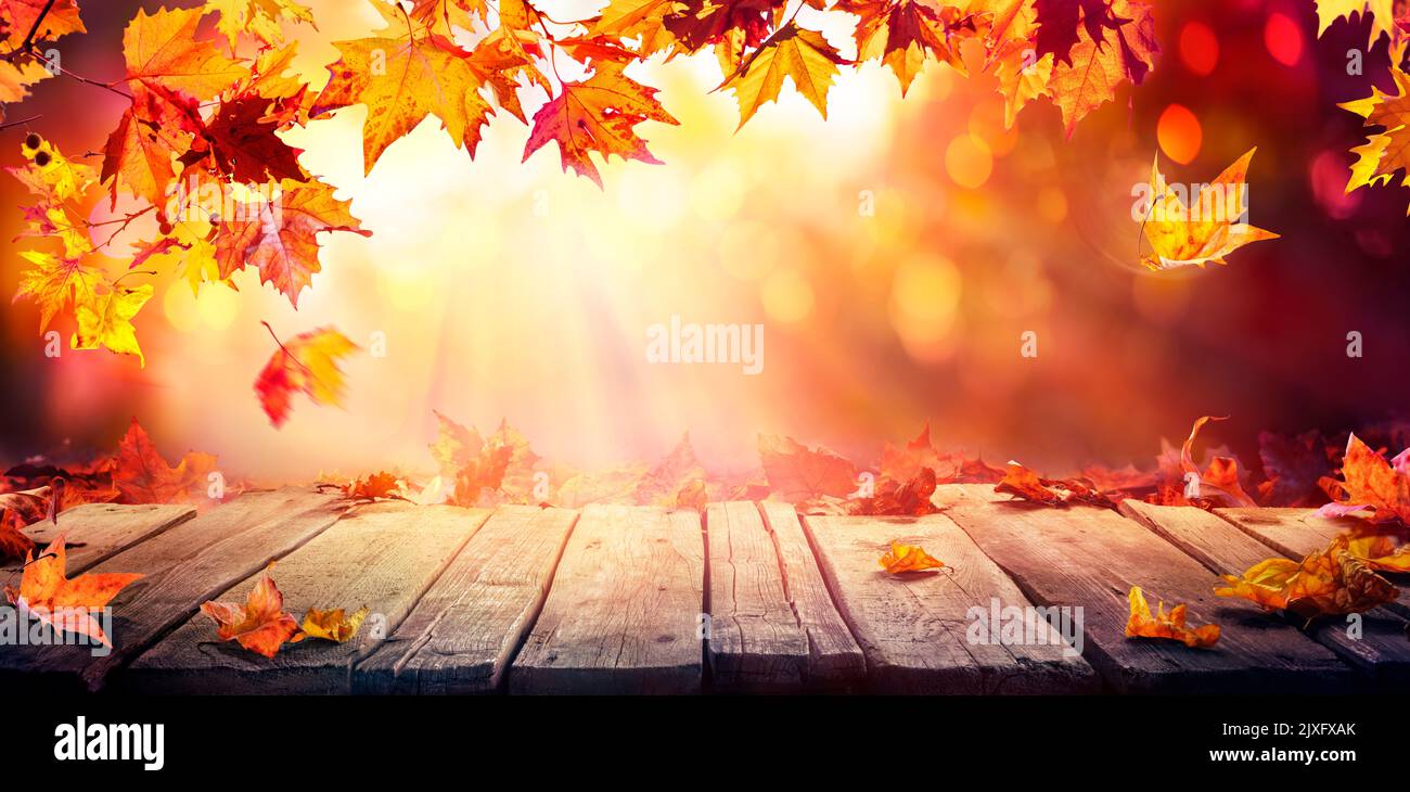 Autumn - Holztisch Mit Orangefarbenen Blättern Bei Sonnenuntergang Auf Defokussierten Abstrakten Hintergrund Stockfoto