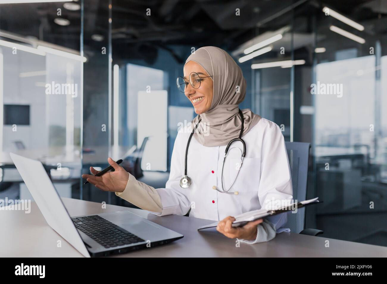 Arzt Online-Beratung mit Patienten, muslimische Frau in Hijab arbeiten aus der Ferne mit Laptop für Videoanruf, Beratung Patienten sitzen in modernen Klinikbüro Stockfoto