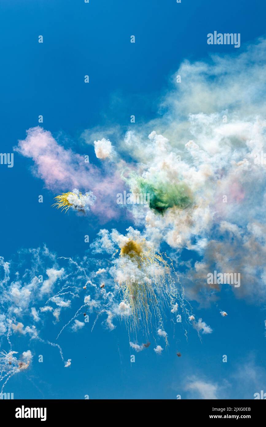 Ein Feuerwerk, das bei hellem Tageslicht gegen einen blauen Himmel explodiert, markiert ein religiöses Fest in einem sizilianischen Dorf Stockfoto