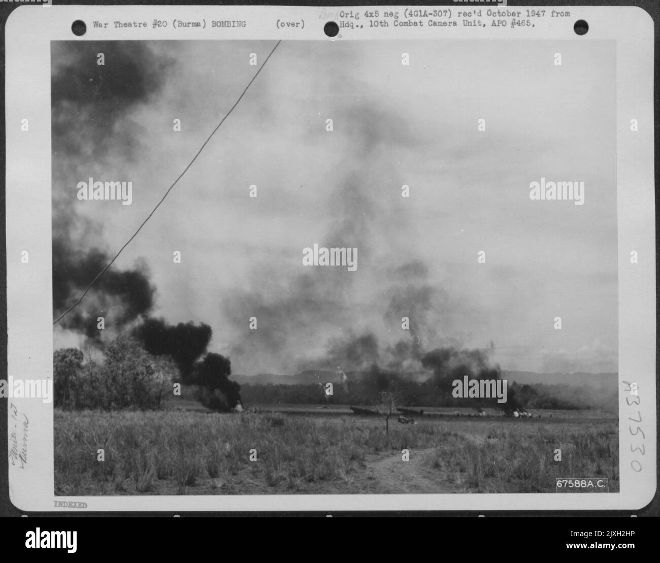 Als die japanische Luftwaffe schließlich am 'Broadway' in Burma anschlug, erwischte sie eine nordamerikanische P-51 der 1. Air Commando Force und versuchte, abzuheben; das Flugzeug brennt in der Mitte des Feldes. The Plane Burning auf der rechten Seite ist Ein britischer Spitfire. Stockfoto