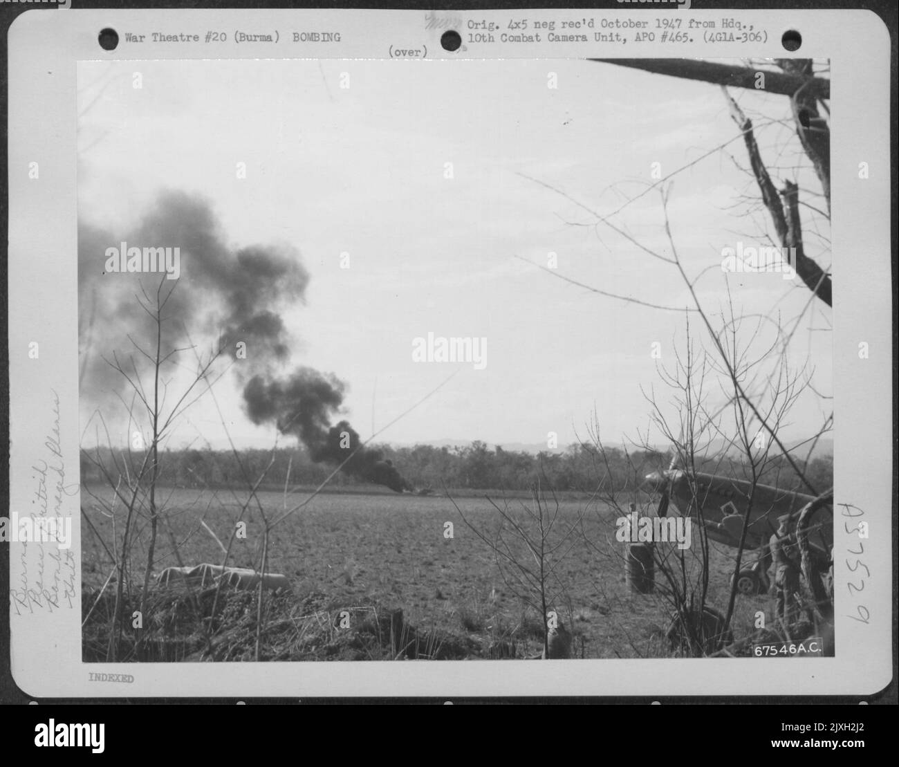 Als die japanische Luftwaffe auf dem Broadway Field in Burma einschlug, erwischte sie eine nordamerikanische P-51 der 1. Air Commando Force, die versuchte, abzuheben. Das Flugzeug Kann Auf Dem Feld Brennen Gesehen Werden. Rechts ist Eine britische Spitfire des Ace Squadron. Stockfoto