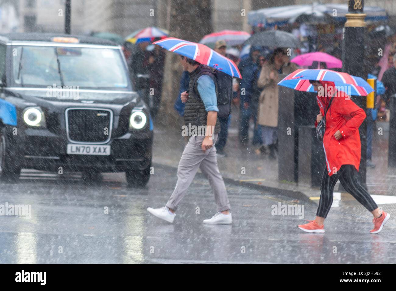 Westminster, London, Großbritannien. 7. September 2022. Heftiger Regen kam in London an. Menschen, die bei der Überquerung von Whitehall unter den Sonnenschirmen von Union Jack geschützt wurden Stockfoto
