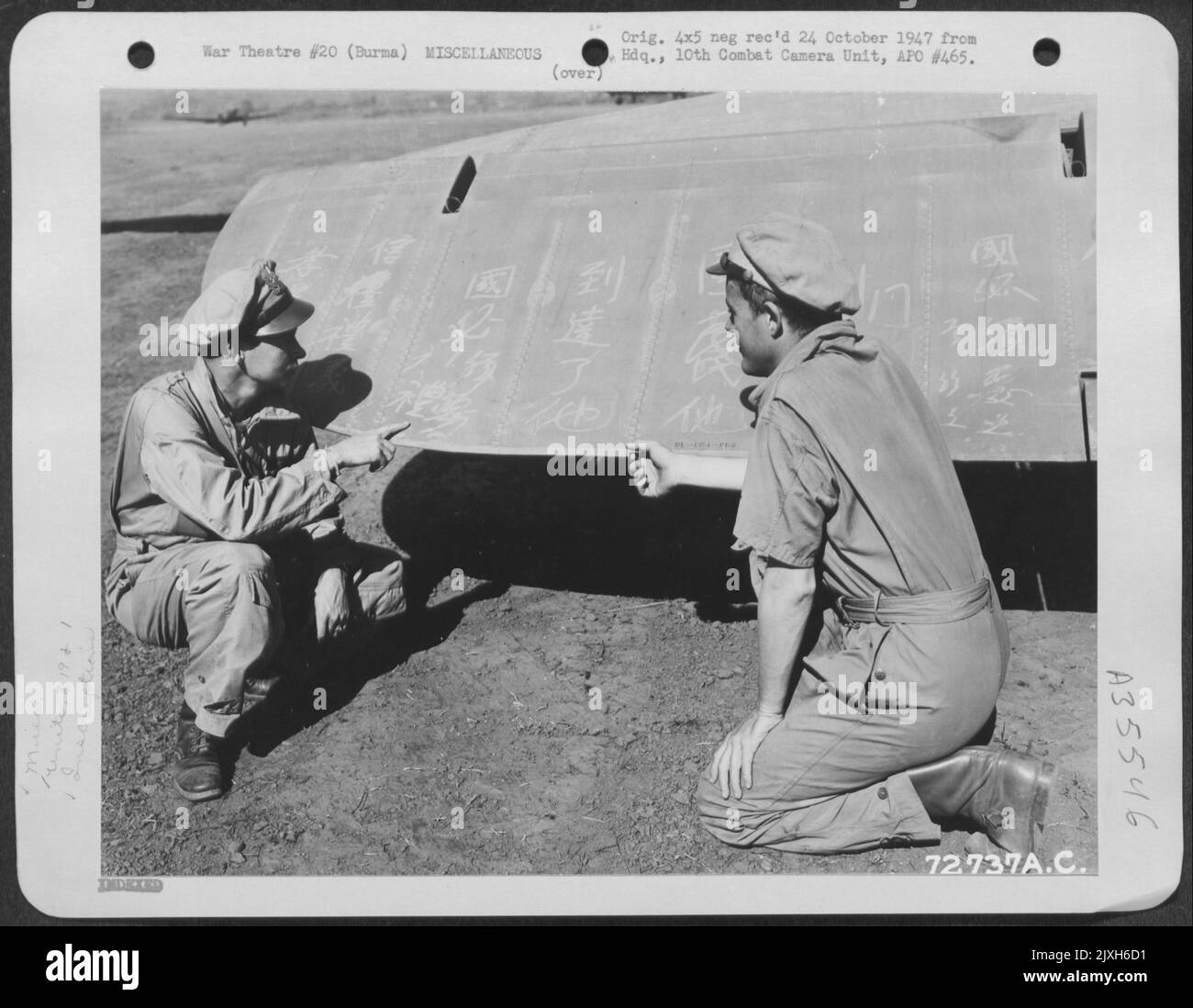 Zwei Offiziere der 319Th Truppe Carrier Squadron, 1. Air Commando Group, studieren die chinesischen Inschriften auf dem Flügel Eines Flugzeugs in Myitkyina, Burma. 13. Dezember 1944. Stockfoto