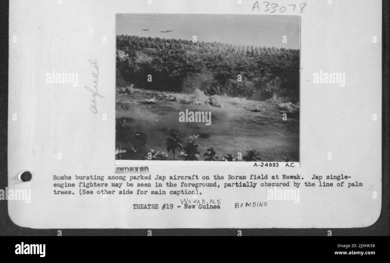 Bomben platzen zwischen geparkten japanischen Flugzeugen auf dem Boram-Feld in Wewak. Japanische einmotorige Kämpfer können im Vordergrund gesehen werden, teilweise verdeckt durch die Palmenlinie. Stockfoto