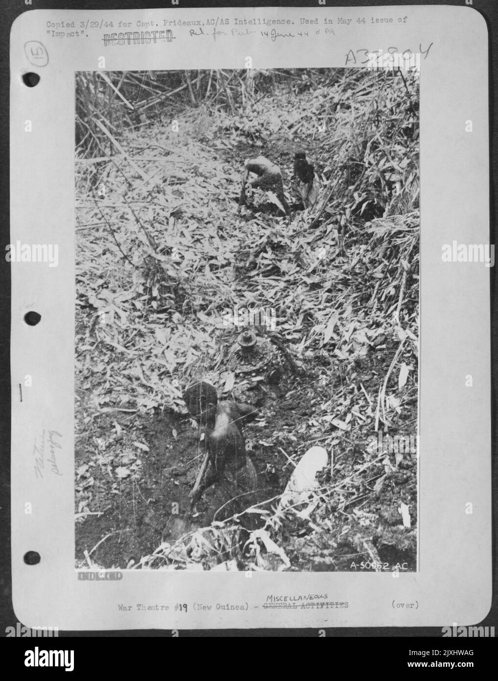 Eingeborene (Bongs) wühlen für japanische Flugzeugteile im Dschungel. Stockfoto