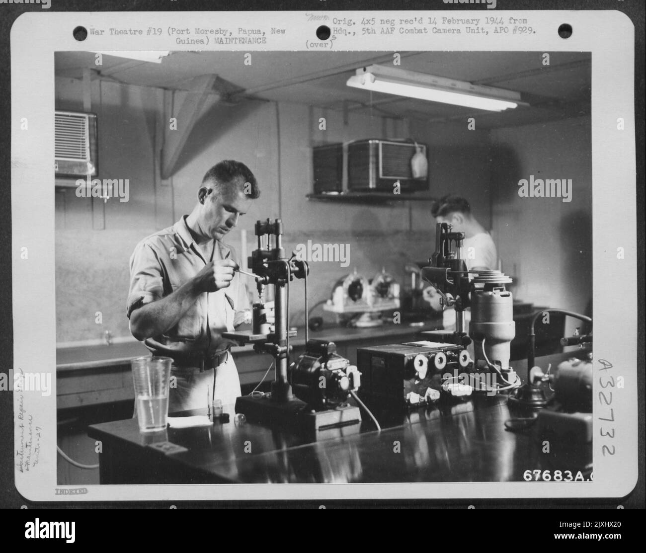 Ein „GI“ der 27. Air Depot Group verwendet eine Bohrpresse, um einen Rotor mit Flugkennzeichen in der Instrumentenwerkstatt zu polieren. Port Moresby Air Depot, Papua, Neuguinea. Stockfoto