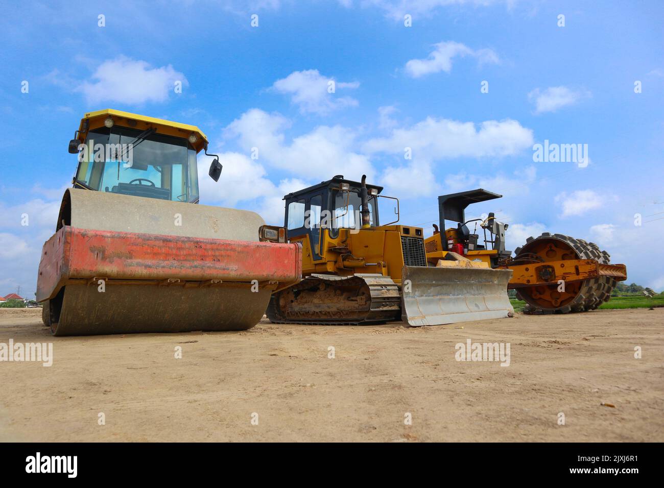 Bulldozer und Straßenwalze mit gelber Farbe, auf Baustelle und Himmel Hintergrund Stockfoto