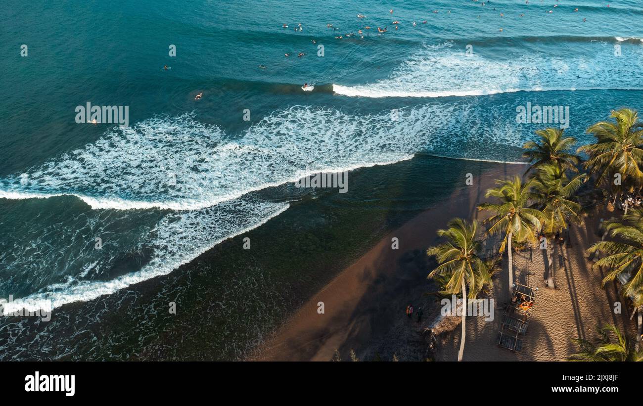 Wunderschöne Aussicht auf das Meer und das Meer mit Surfern, die auf die Wellen warten. Stockfoto