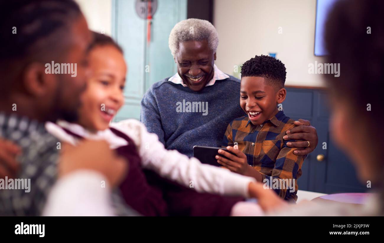 Großvater Mit Enkelkindern, Die Zu Hause Auf Dem Mobiltelefon Spielen Stockfoto