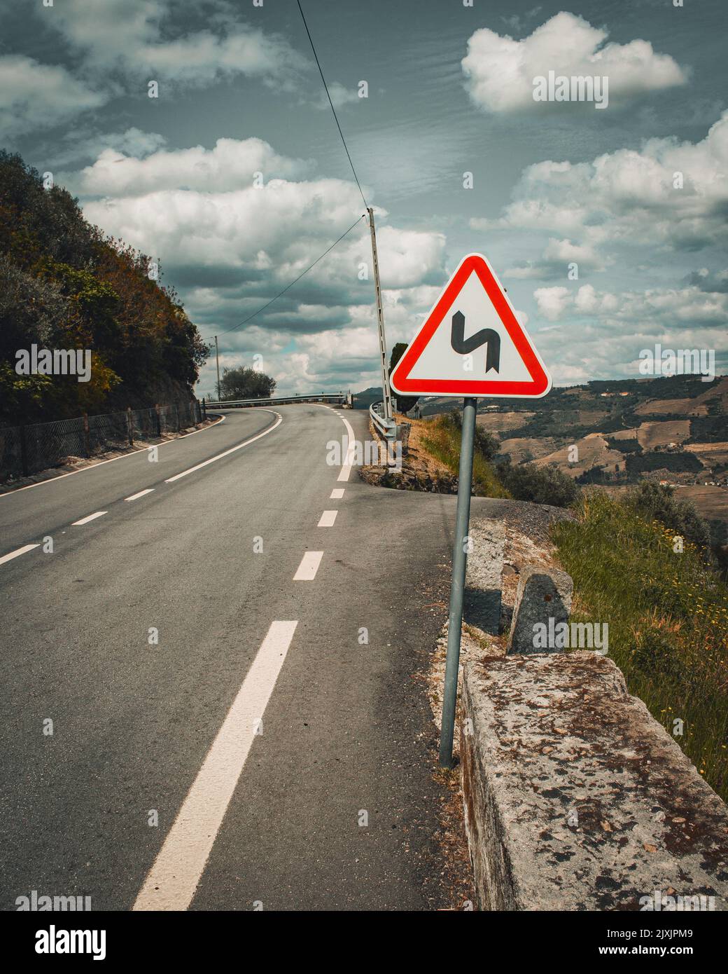 Gefährliche Zickzackkurven signalisieren auf einer Straße mitten auf dem portugiesischen Hügel des Douro-Flusses. Stockfoto