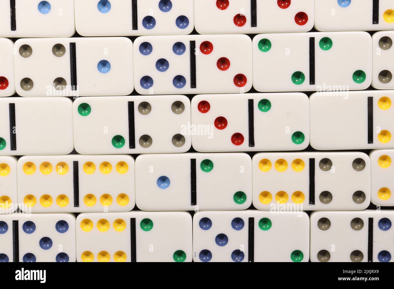 Weiße Domino-Stücke mit farbigen Punkten über einem schwarzen Holztisch Stockfoto