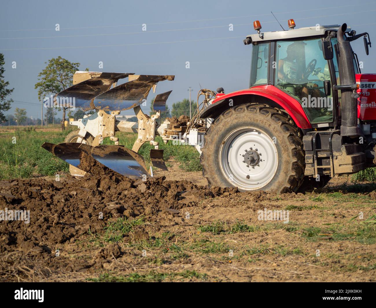 4K Video von rotem Traktor, der das Land auf dem Land pflügt. Stockfoto