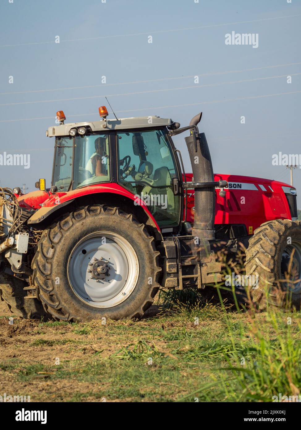 4K Video von rotem Traktor, der das Land auf dem Land pflügt. Stockfoto