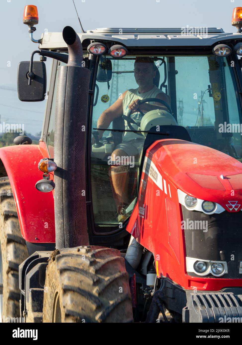 4K Video von rotem Traktor, der das Land auf dem Land pflügt. Stockfoto