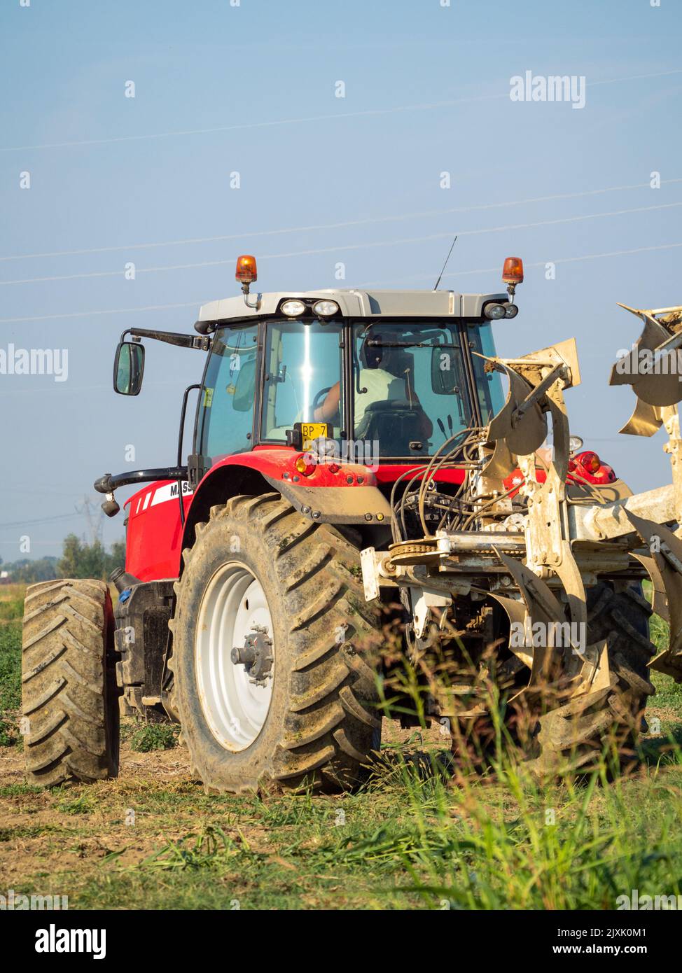 4K Video von rotem Traktor, der das Land auf dem Land pflügt. Stockfoto