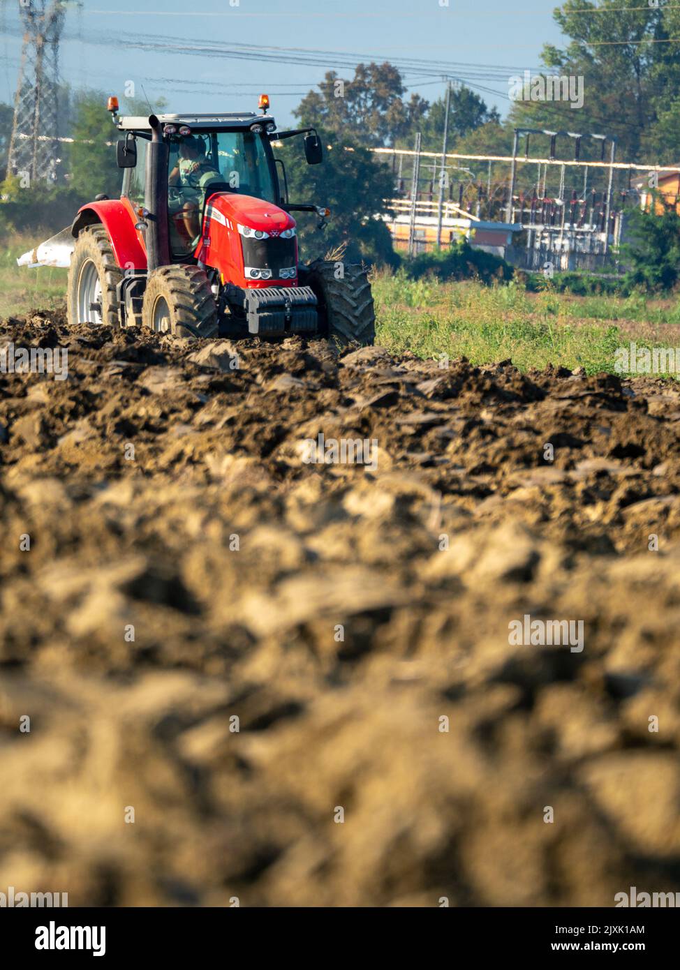 4K Video von rotem Traktor, der das Land auf dem Land pflügt. Stockfoto