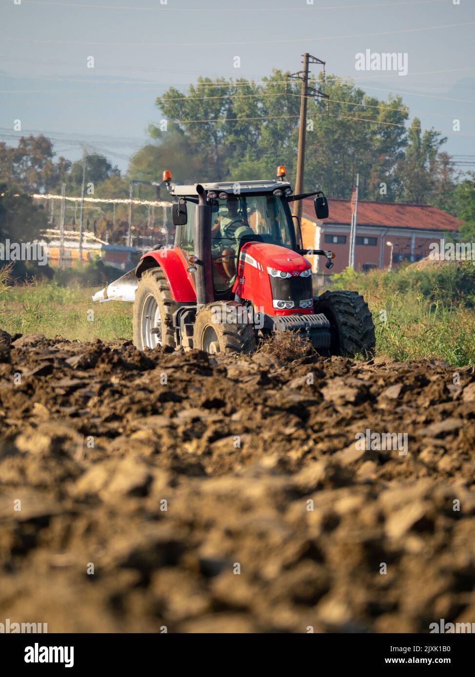 4K Video von rotem Traktor, der das Land auf dem Land pflügt. Stockfoto