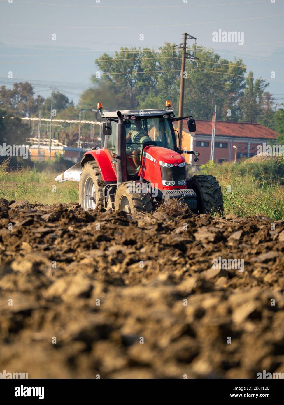 4K Video von rotem Traktor, der das Land auf dem Land pflügt. Stockfoto