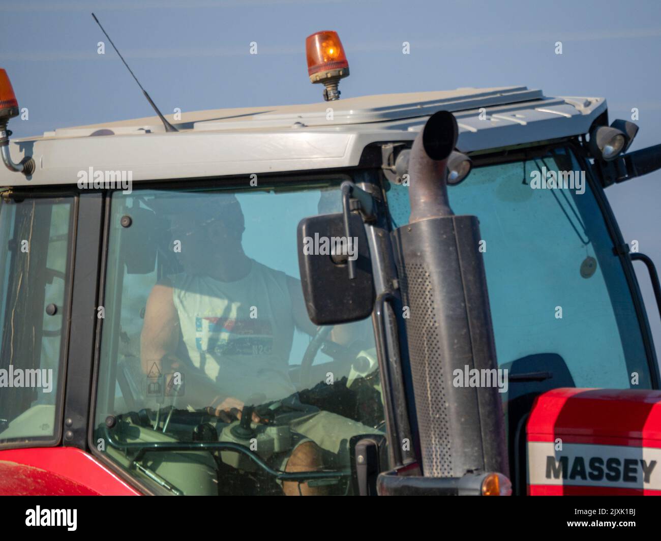 4K Video von rotem Traktor, der das Land auf dem Land pflügt. Stockfoto