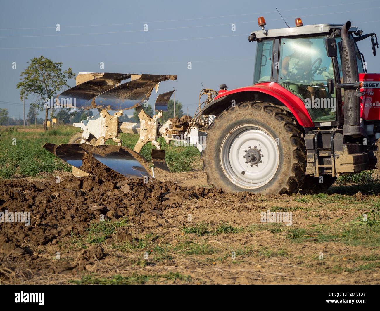 4K Video von rotem Traktor, der das Land auf dem Land pflügt. Stockfoto