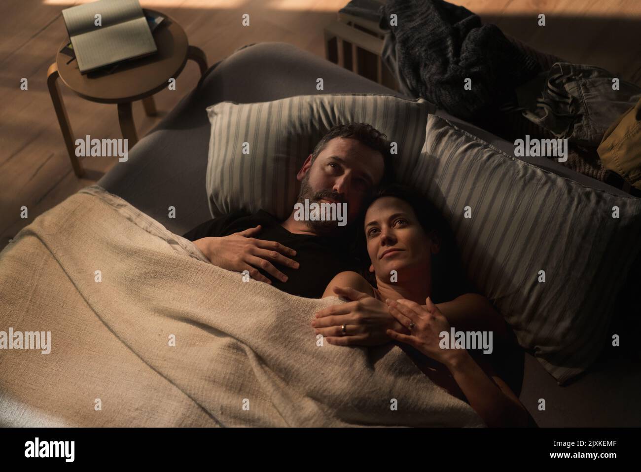 Mittelerwachsenes Paar, das nachts im Bett liegt und das Konzept von Partnerschaft und Intimität umarmt. Stockfoto