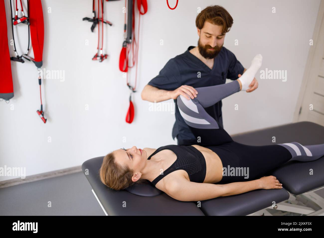 Physiotherapeutin, die mit den Beinen einer jungen Patientin im Rehabilitationszentrum arbeitet Stockfoto