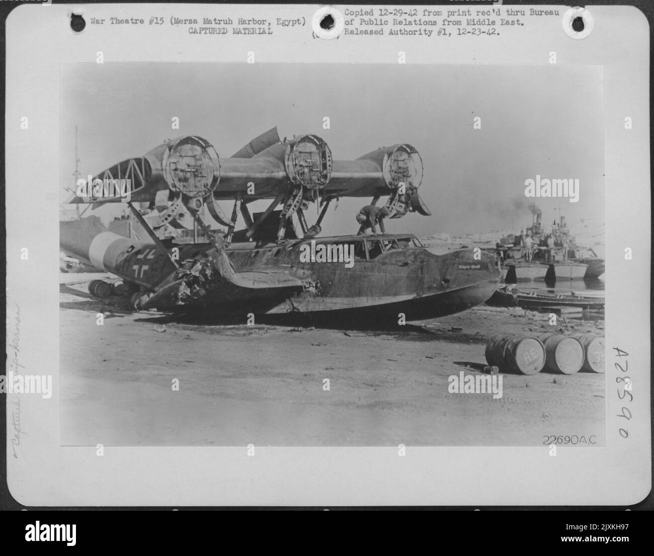 Ein deutsches Flying Boat, das auf dem Wasser im Hafen von Mersa Matruh in Ägypten gefangen wurde, wurde von den Kugeln durchlöchert, die von niedrig fliegenden alliierten Kämpfern abgefeuert wurden. Ein Offizier der amerikanischen Luftwaffe untersucht das fliegende Schiff, nachdem die Deutschen es an Land geschleppt und ausgezogen hatten Stockfoto