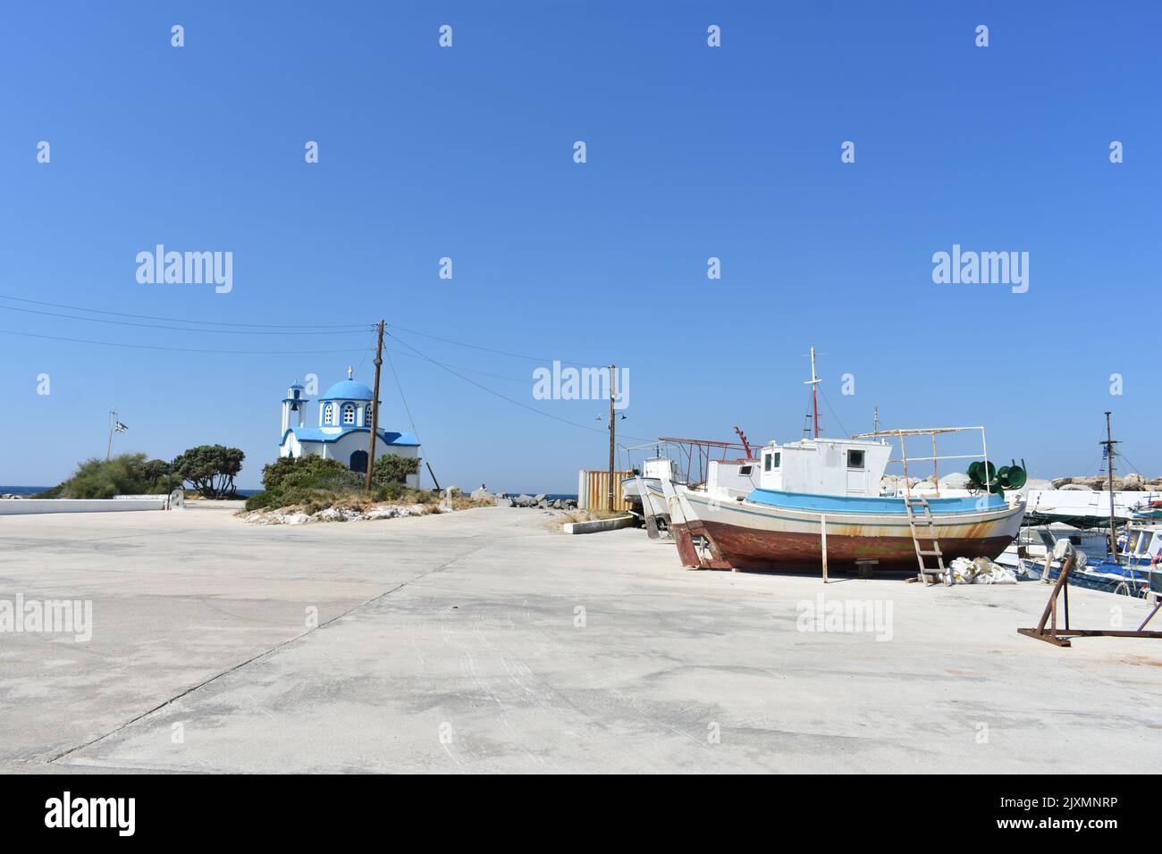 Hafen von Gialiskari am Meer auf der Insel Ikaria mit griechisch-orthodoxer Analipsi-Kirche von Gialiskari mit Fischerbooten, Insel Ikaria, Griechenland, Europa Stockfoto