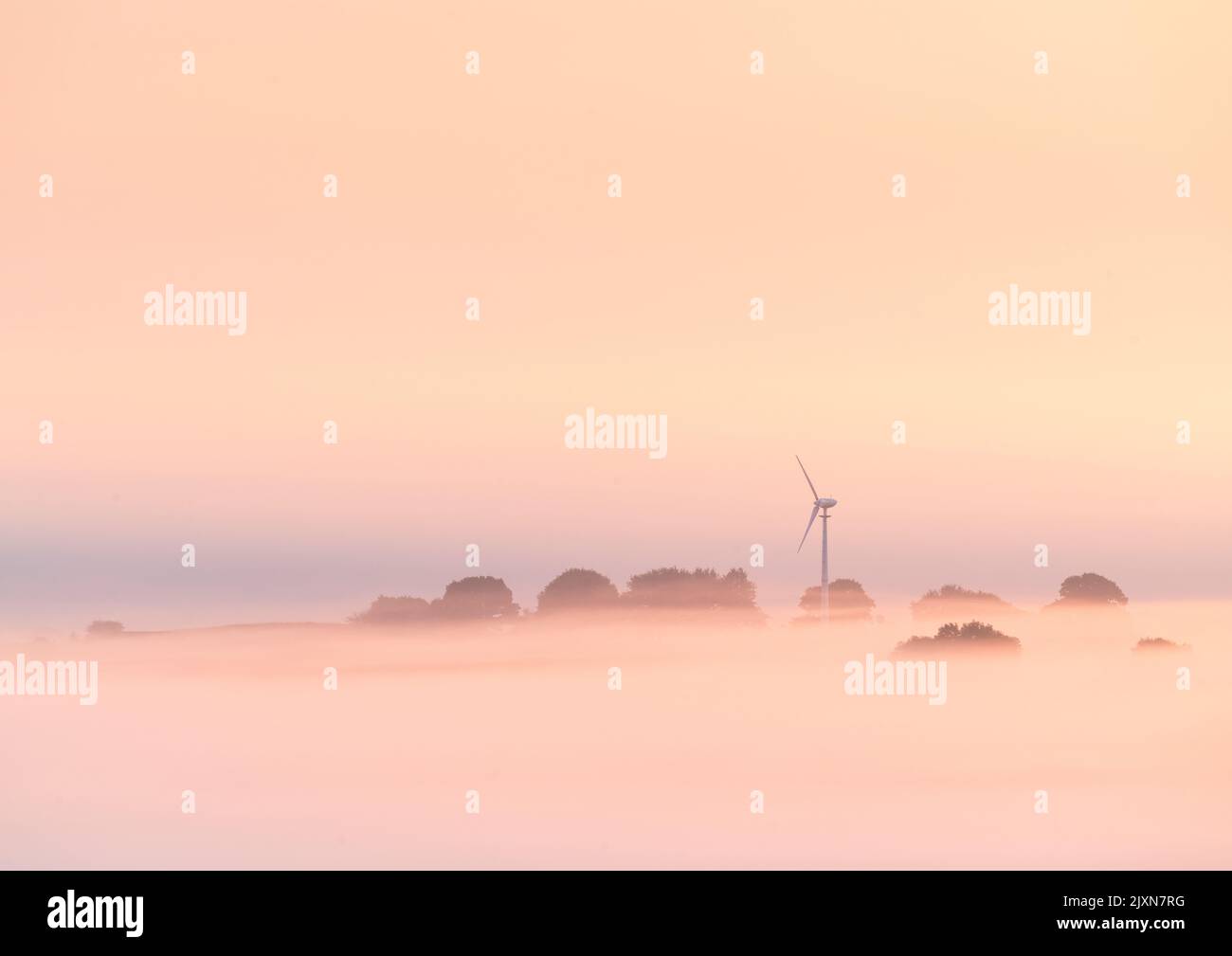 Eine einzelne Windturbine ist über dem Nebel während eines wunderschönen pastellfarbenen Sonnenaufgangs am Rande des Wals of York im Spätsommer sichtbar. Stockfoto