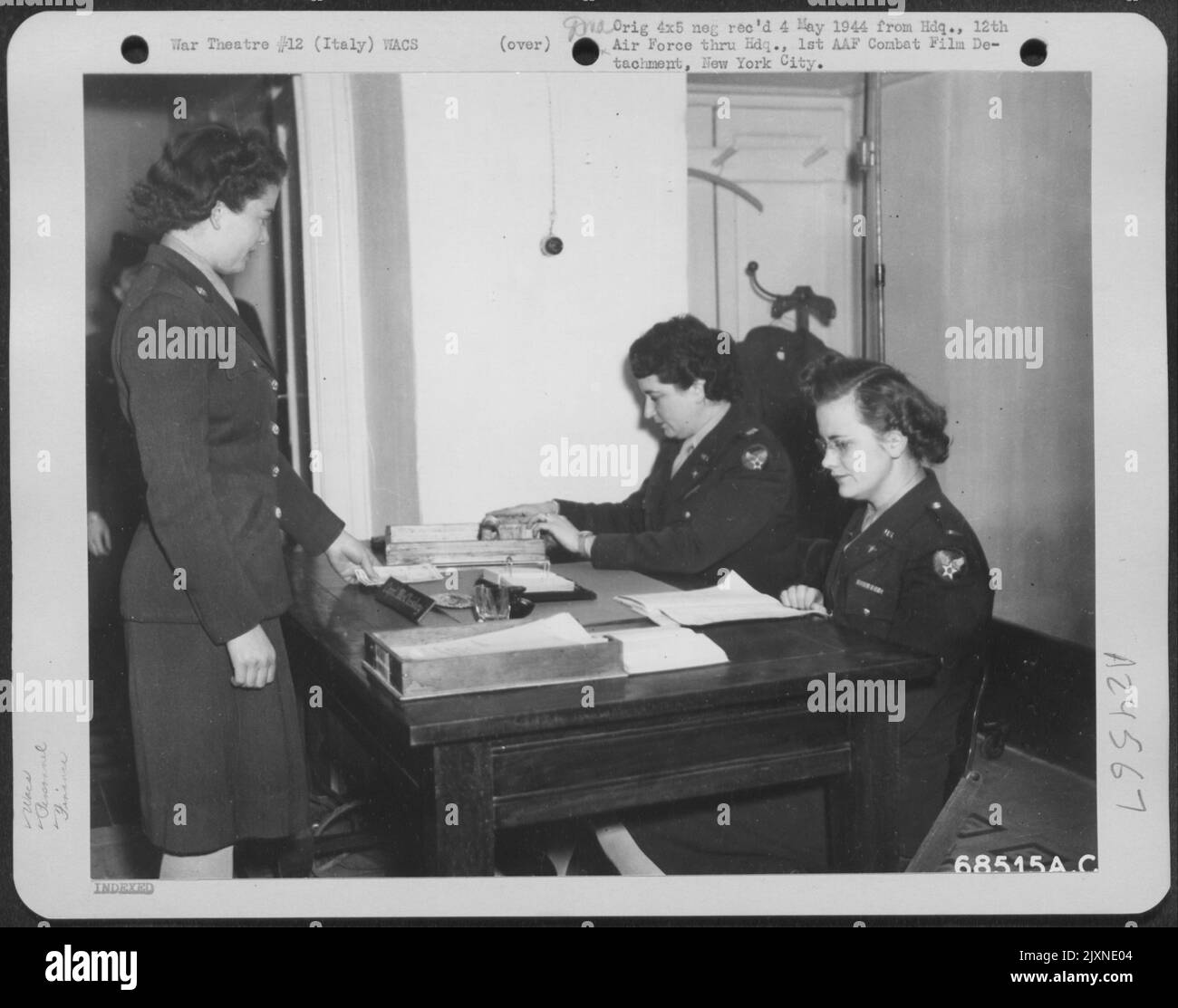 Nach Einem bissigen Gruß, Pvt. Mary V. Koehl aus Akron, Ohio, erhält ihren monatlichen Lohn vom Kommandanten der Air WAC Platoon'S am 12. Air Force Headquarters, Capt. Verna A. McCluskey aus Birmingham, Alabama (links), während 1. LT. Mary Crook aus Minneapolis Stockfoto