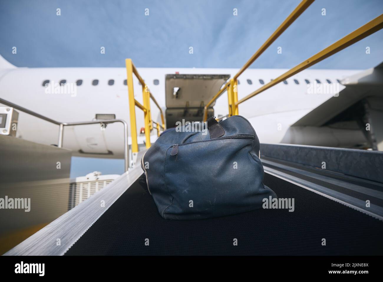 Verladung des Gepäcks ins Flugzeug. Blauer Beutel auf dem Förderband am Flughafen. Stockfoto