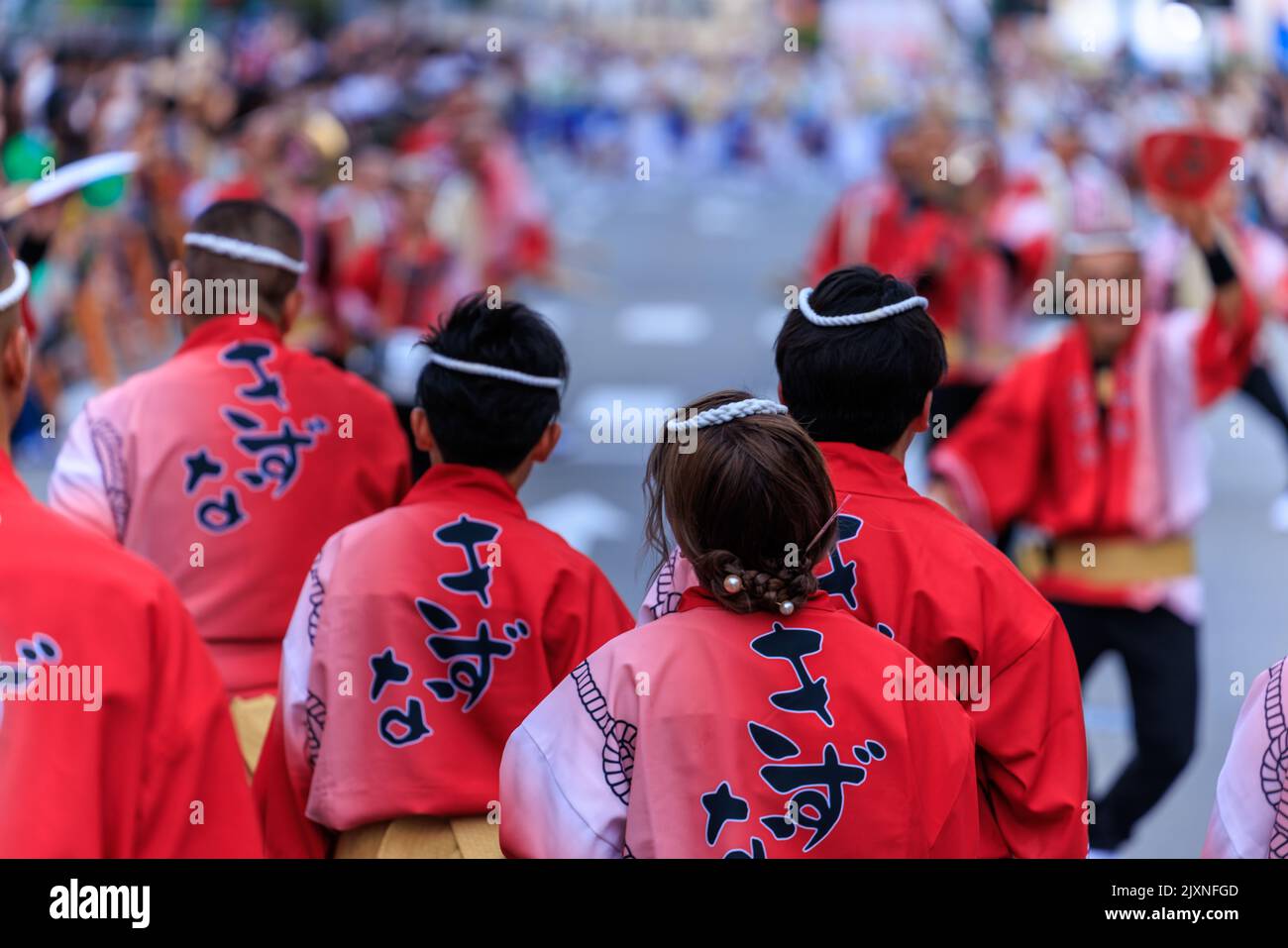 Tokushima, Japan - 12. August 2022: Darsteller in leuchtendem Rot, traditionelle Kleidung, beobachten die Parade beim Awaodori-Festival Stockfoto