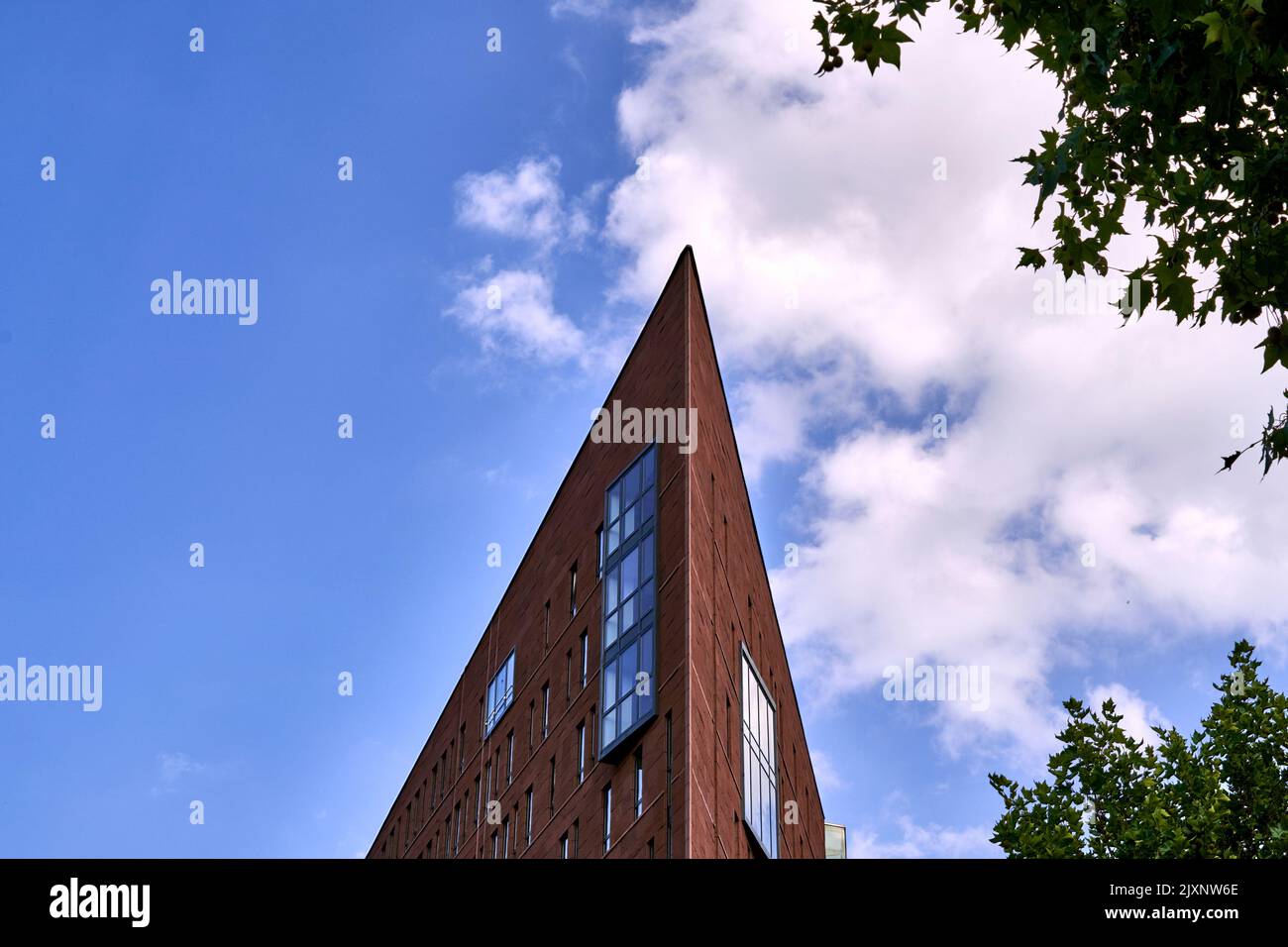 Futuristisches, schmal zulaufendes hohes Gebäude vor bewölktem Himmel Stockfoto Futuristisches, schmal zulaufendes hohes Gebäude vor bewölktem Himmel Stockfoto