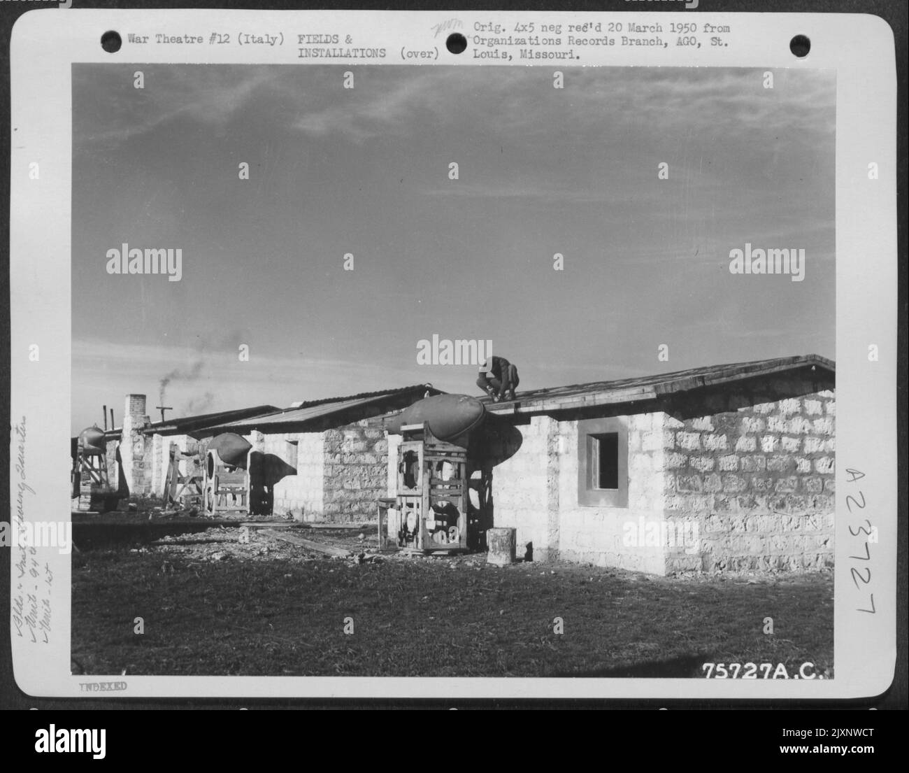 Ein Mitglied der 94. Fighter Squadron, 1. Fighter Group, arbeitet auf dem Dach seiner aus Steinblöcken gebauten Steinvilla auf einem Flugplatz irgendwo in Italien. Der Kraftstofftank Hält Kraftstoff Für Sein Heizsystem Im Haus. Stockfoto