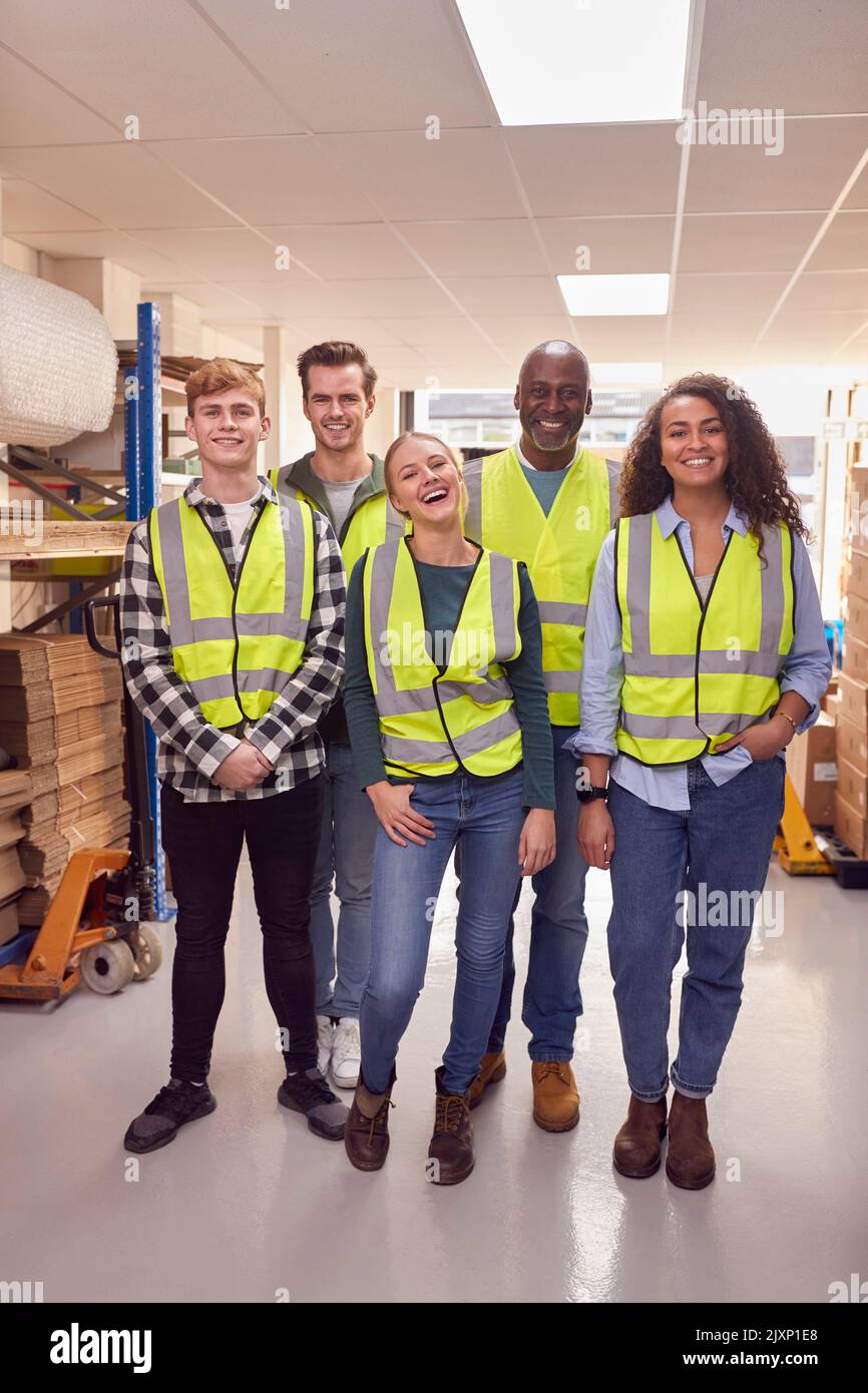 Portrait Eines Multikulturellen Teams, Das Hi-Vis Sicherheitskleidung Trägt Und In Einem Modernen Lagerhaus Arbeitet Stockfoto