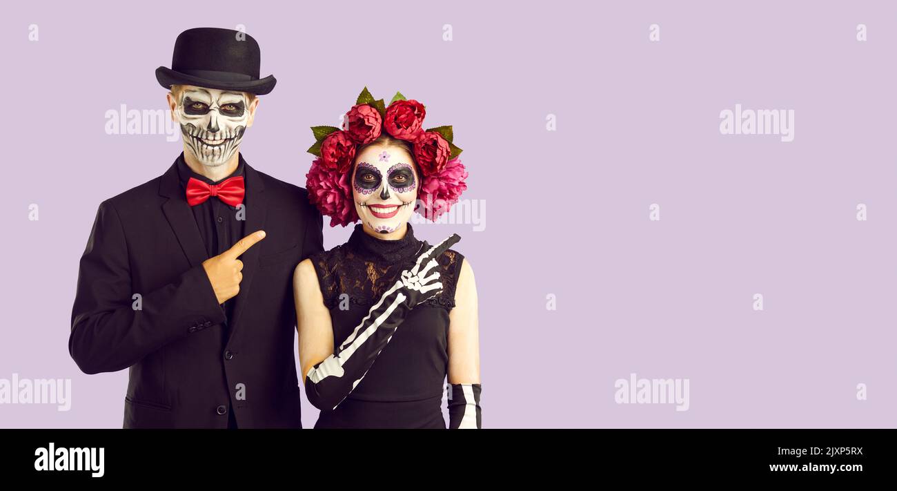 Paar in kreativen Kostümen zeigen Finger auf Kopie Raum empfehlen etwas Halloween-Thema. Stockfoto