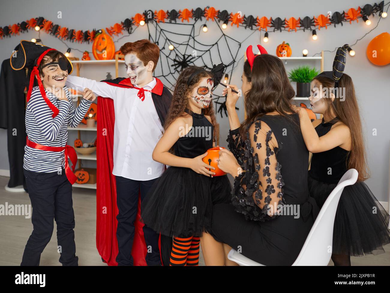 Künstler macht gruseliges Make-up für eine Gruppe von Kindern auf einer lustigen Halloween-Party zu Hause Stockfoto