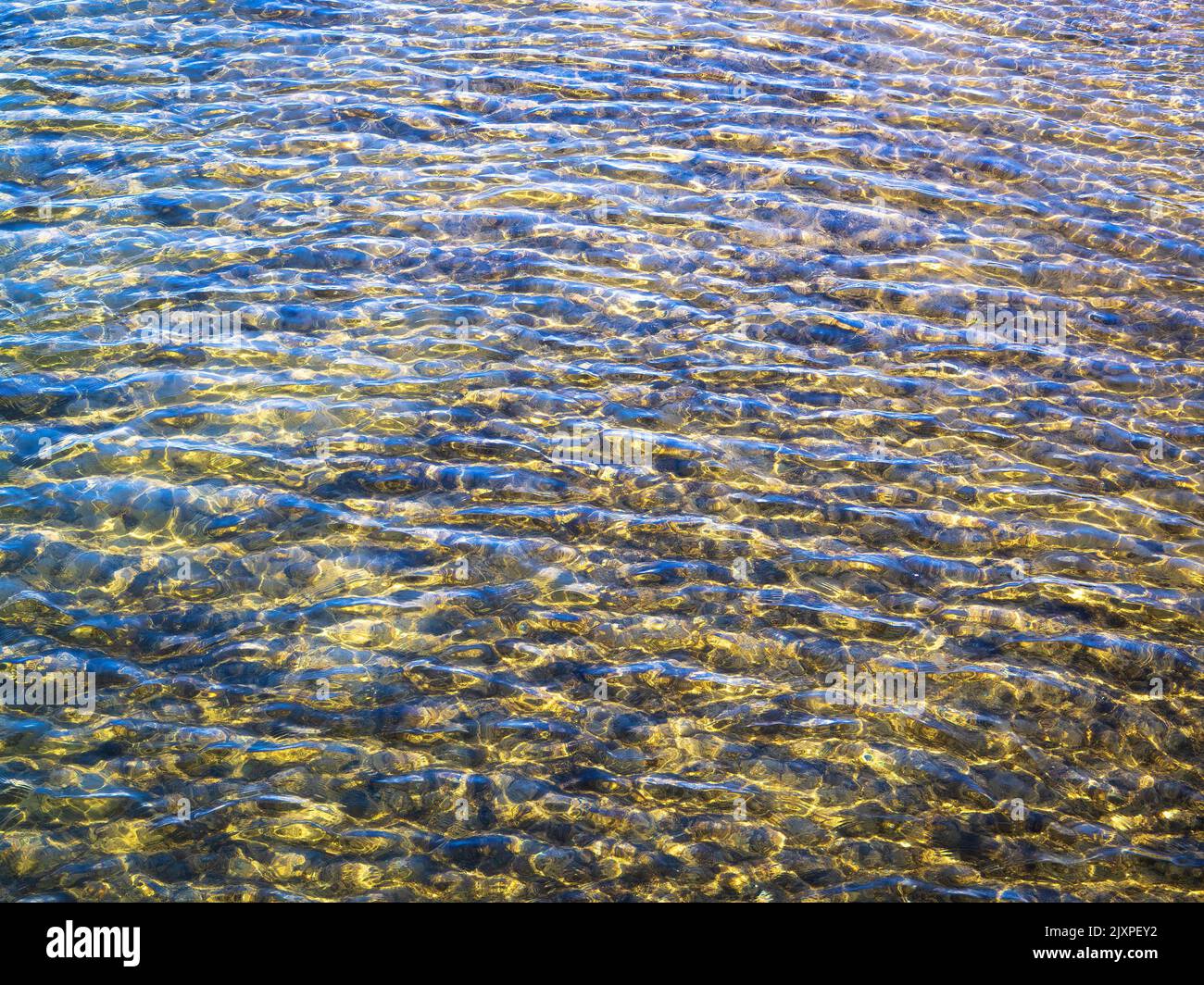 Bei Ebbe schimmern die Farben des Wasserlichts durch Gelbtöne zu Brauntönen in den Untiefen. Stockfoto