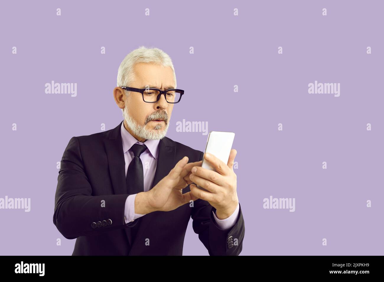 Studio-Porträt eines ernsthaften Geschäftsmannes in Anzug und Brille mit Mobiltelefon Stockfoto