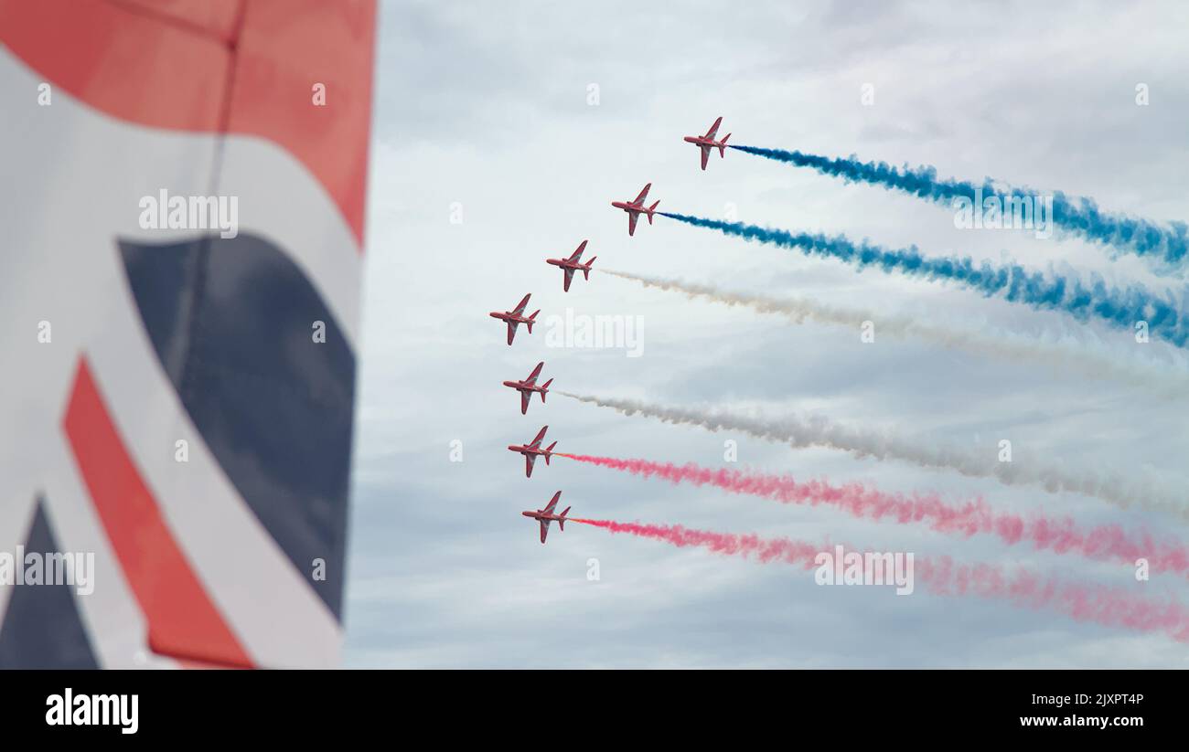 Royal Air Force Red Arrows Aerobatic Display Team fliegt in Formation mit rotem, weißem und blauem Rauch mit dem Schwanz Eines roten Pfeils im Vordergrund, B Stockfoto