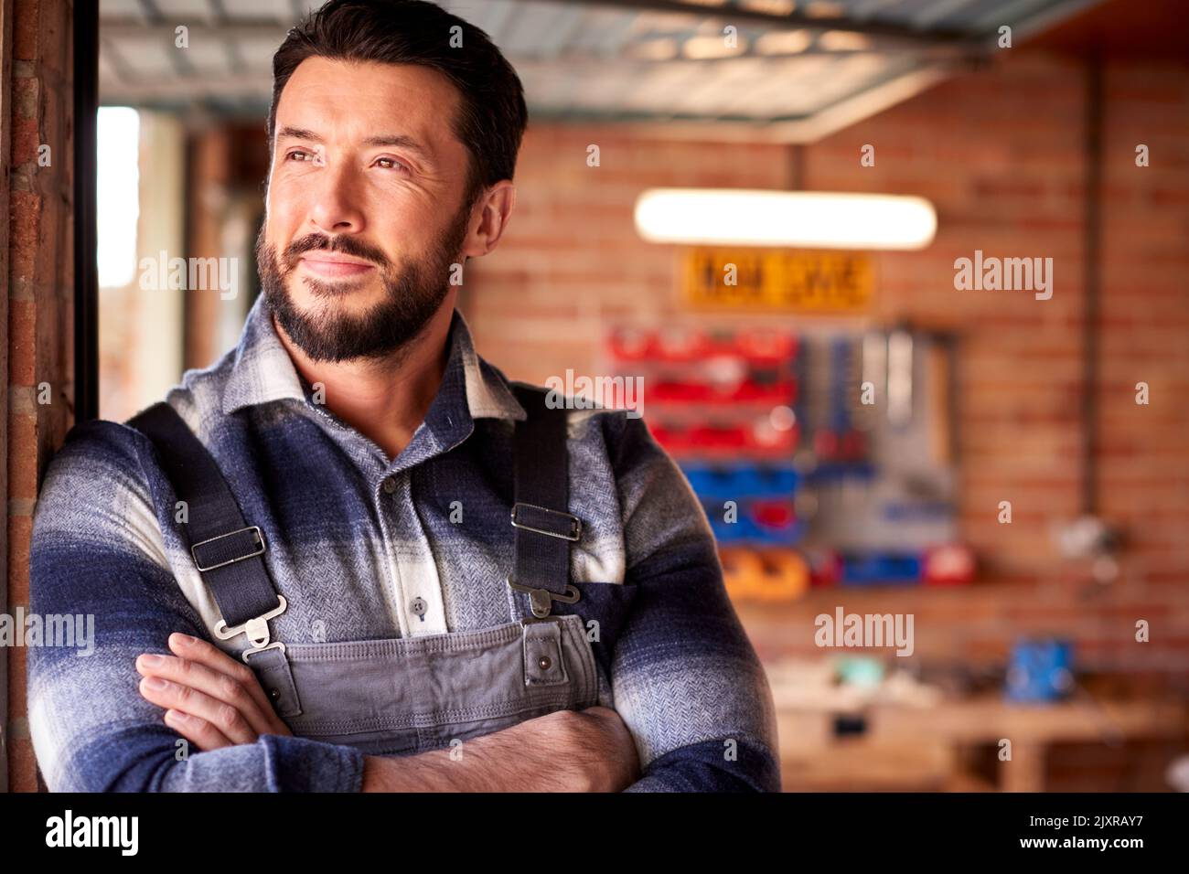 Porträt Eines Mannes, Der Overalls In Der Garage Werkstatt Zu Hause Trägt Stockfoto
