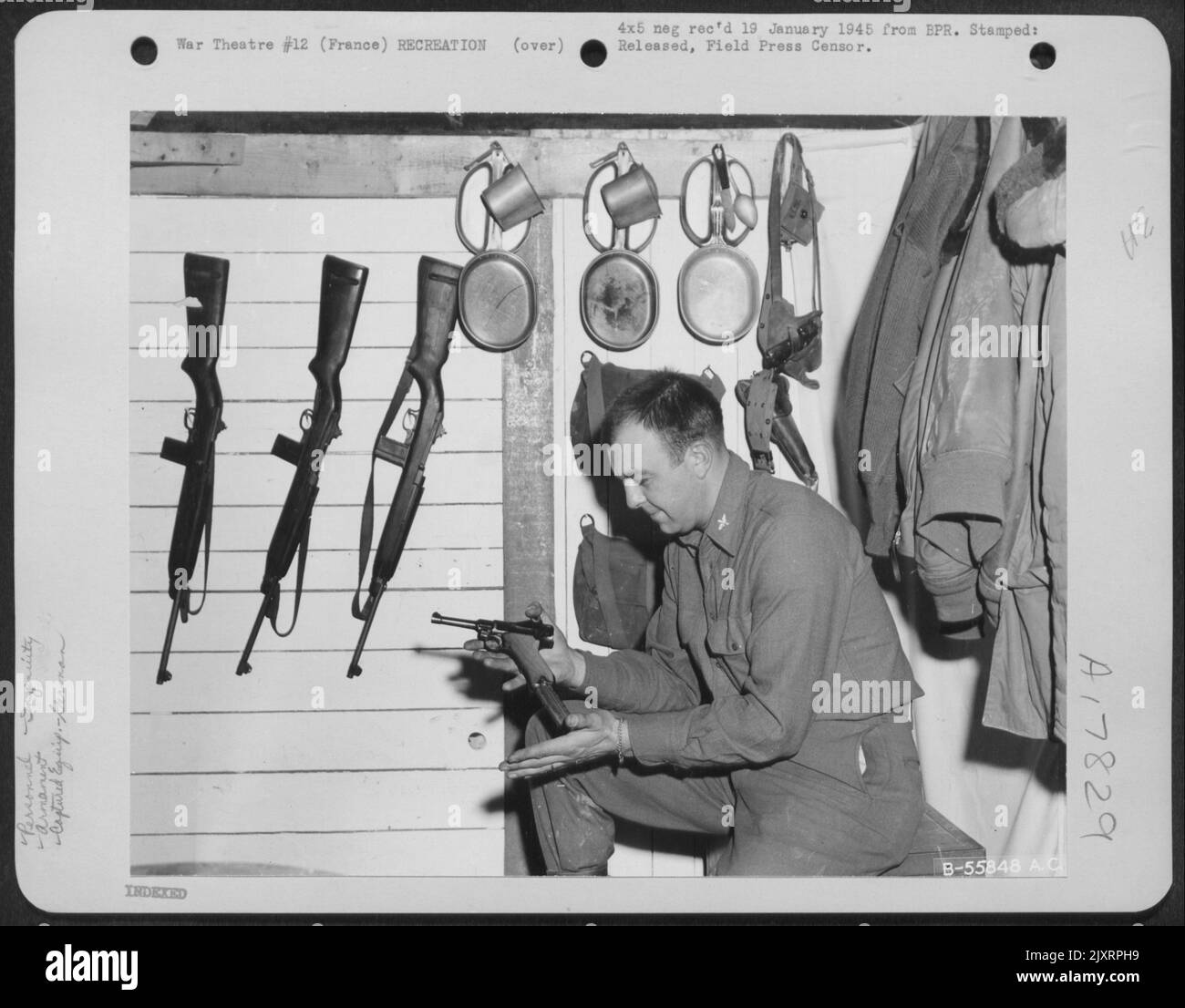 LT. Wayne E. Kommentar von Fort Wayne, Indiana inspiziert eine gefangene deutsche Luger-Pistole in einer Ecke des zweistöckigen 'Shackteau', das er und andere in Frankreich stationierte Rmen gebaut haben. Stockfoto
