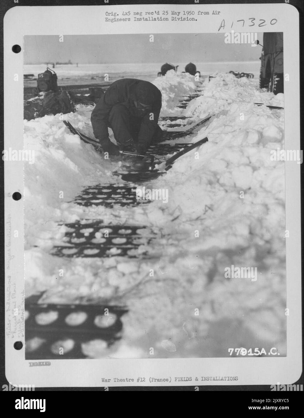 Trotz des Schneefalls auf der Luftwaffenstation A-72 in Peronne, Frankreich, verwendet Ein Mitglied des 833Rd Engineer Aviation Battalion eine Acetylenbrenner in Schweißbohrplanken während des Baus eines Flugfeldes. Januar 1945. Stockfoto