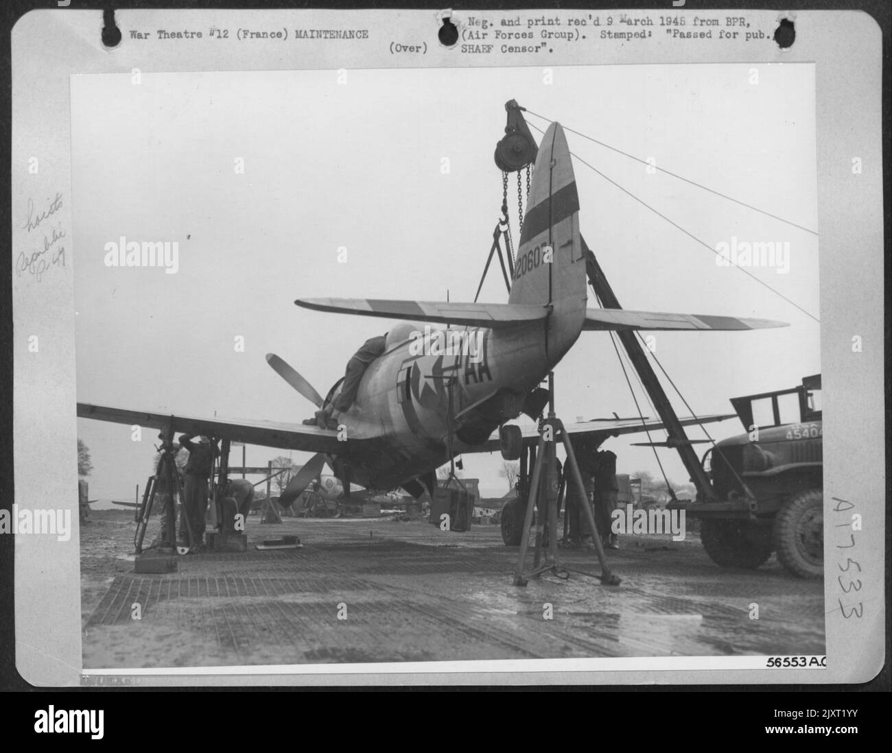 Crew Chiefs nutzen ihren Einfallsreichtum, wenn sie die Geschütze eines ersten P-47 Jagdbombers der TAC AF Republic auf diesem fortgeschrittenen Feld in Frankreich unter die Augen trugen. Das Flugzeug im Ebenen Flug hält ein G.I. LKW mit einem Kran, der das Heck abwiegt Stockfoto