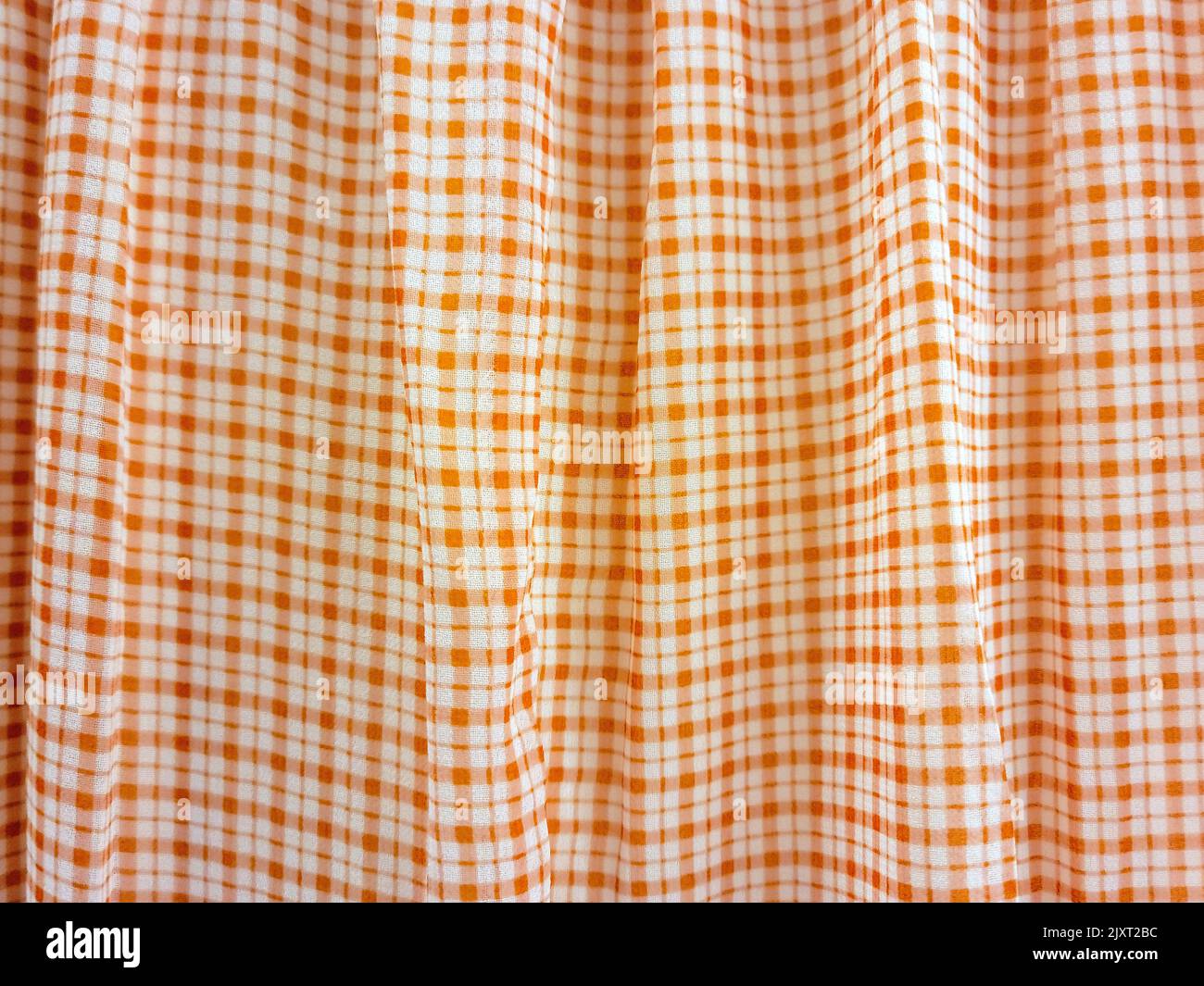Nahaufnahme von Stofffalten mit orangefarbenem Karomuster Stockfoto